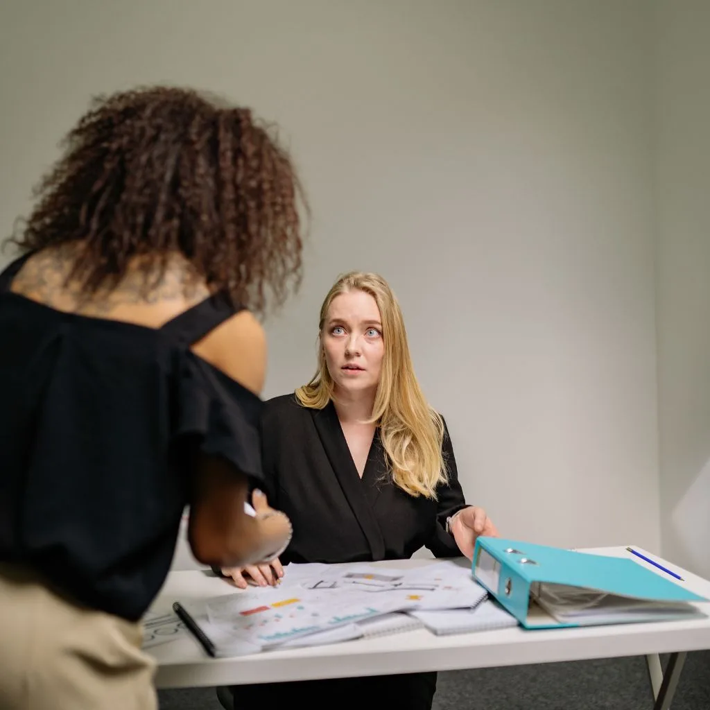 person sitting with a lot of document in front and looking overwhelmed