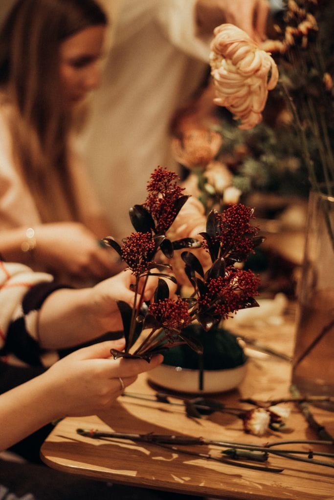 Adults arranging colorful seasonal flowers during a grief nature workshop.